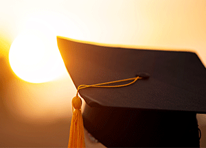 person wearing graduation hat at sunset