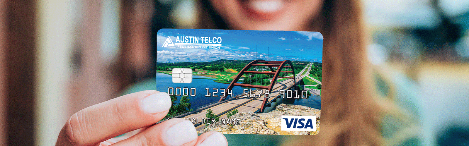 woman holding austin telco visa card and smiling in background