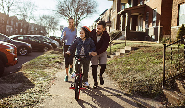 Family watching daughter ride a bike