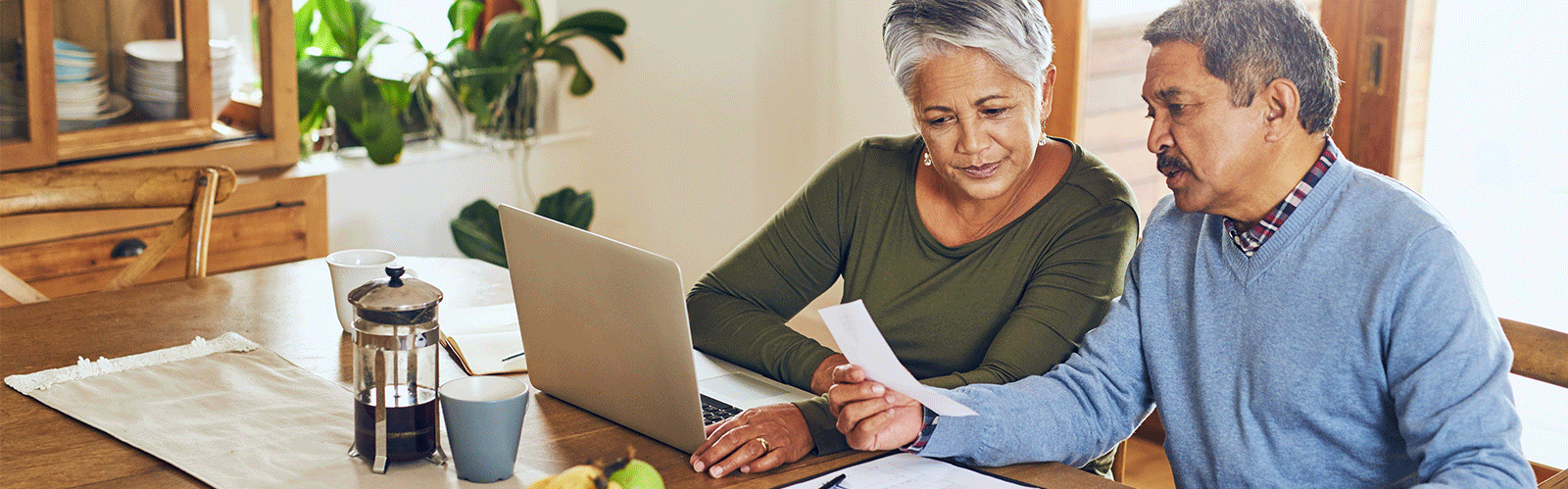 couple on laptop and looking at paper at a table