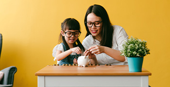 Mom and daughter putting money in piggy bank