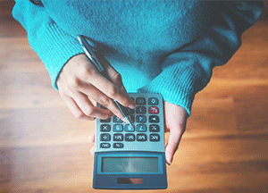 person using calculator with pen in hand