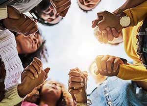 Group of people holding hands in a circle.