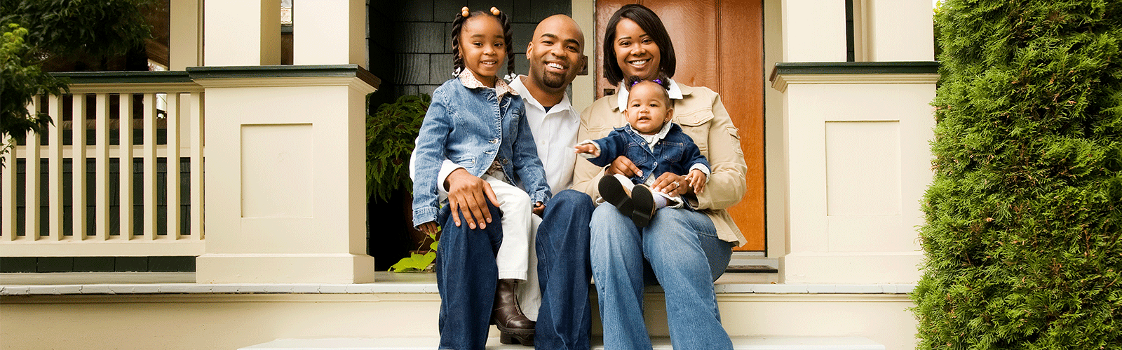 african american family sitting in front of home