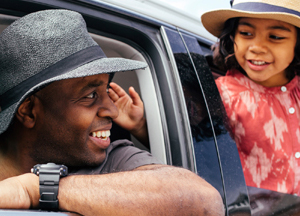 father smiling back at daughter in car