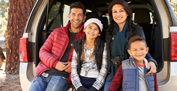 family in back of van and smiling