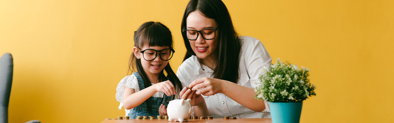 Mom and daughter putting money in piggy bank