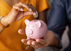 individual placing coin in piggy bank